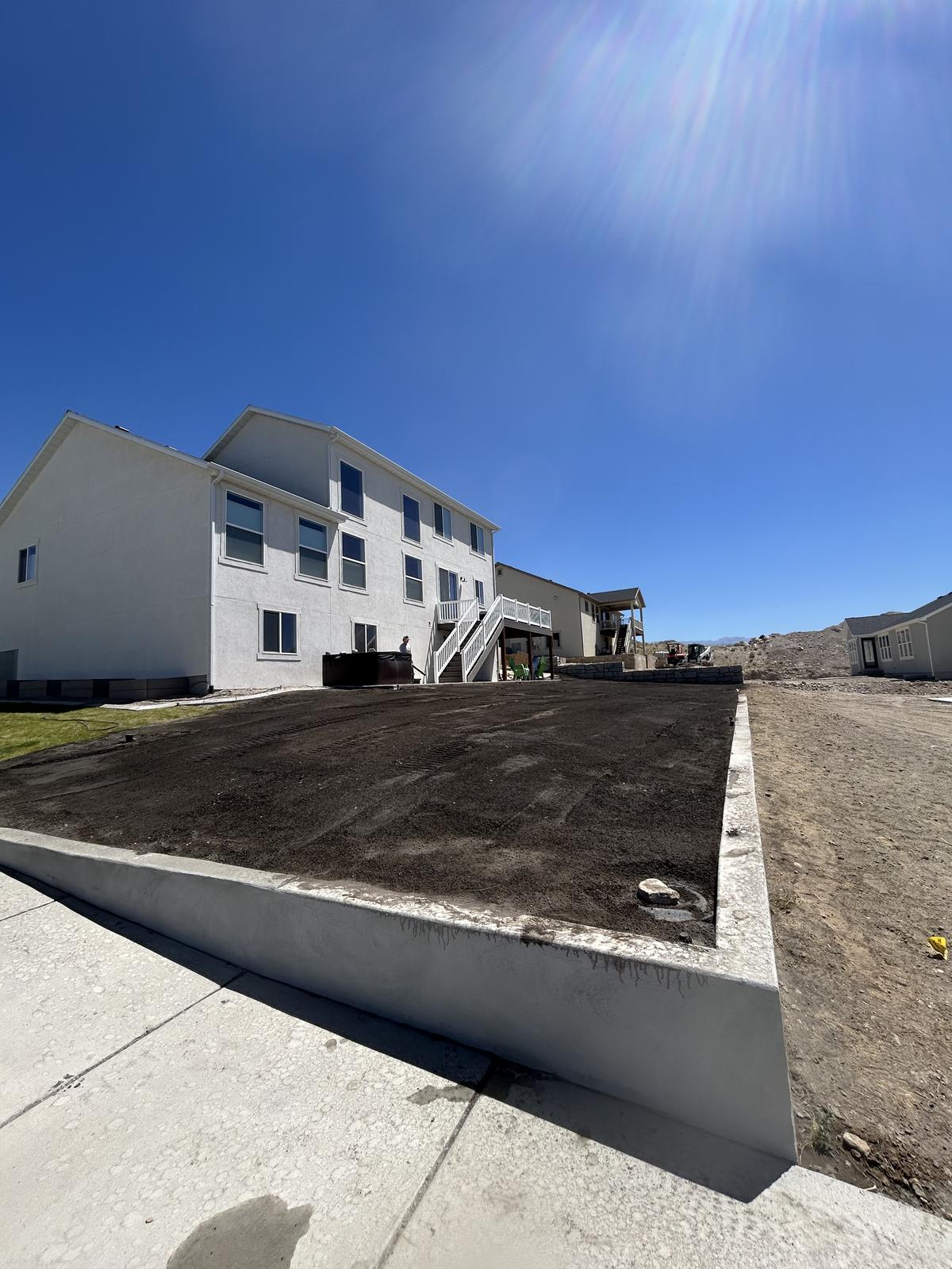 Fresh topsoil spread inside new concrete curbing, ready for sod